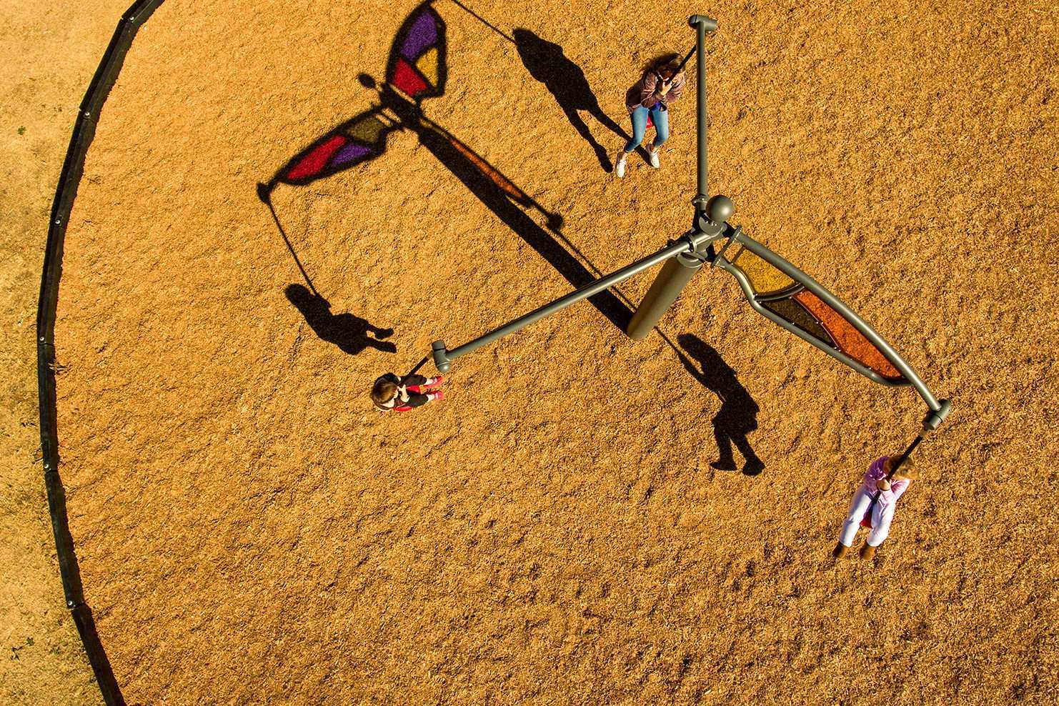 Image of three children riding a swing carousel