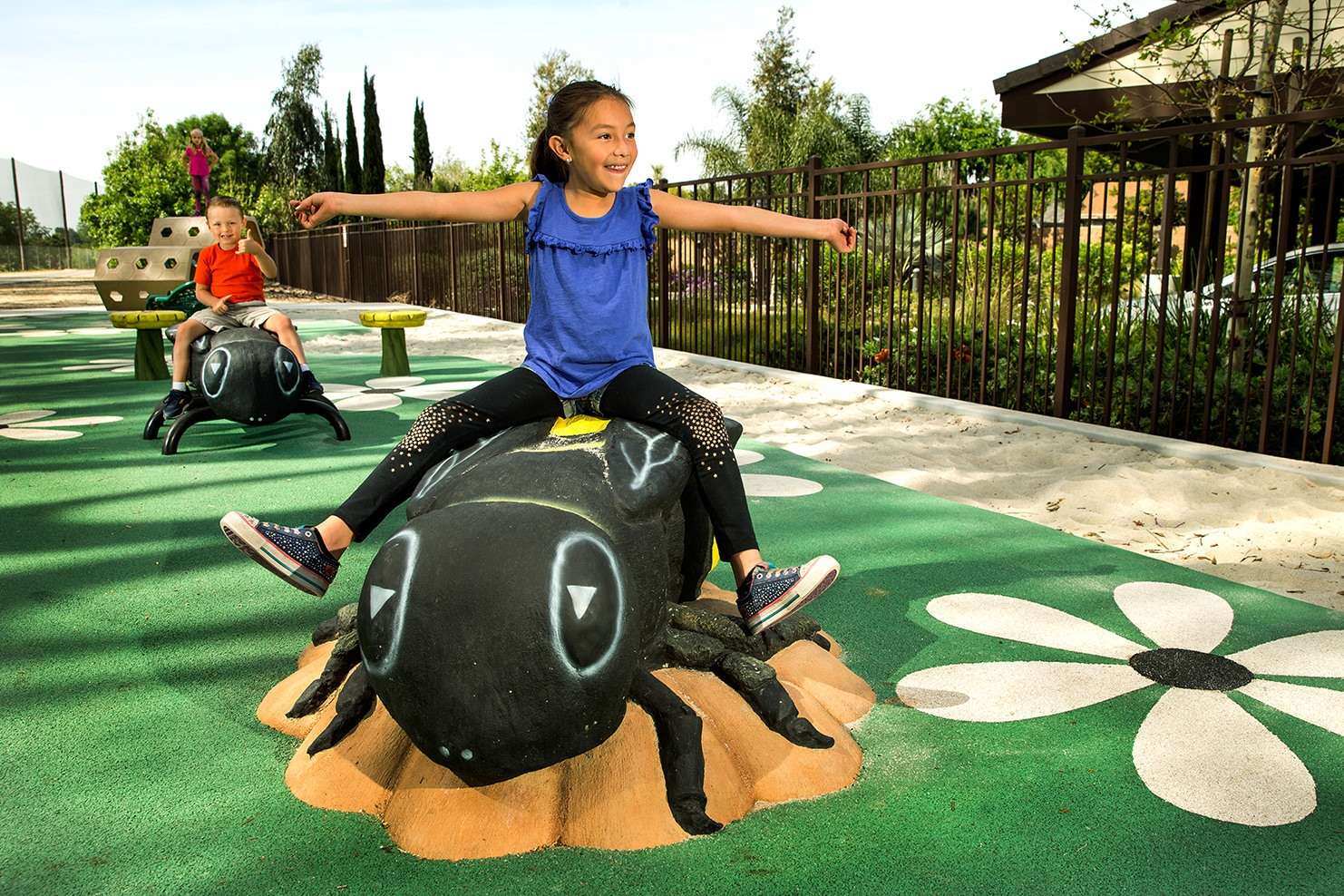 Image of a child in a blue shirt riding a statue of a black ant