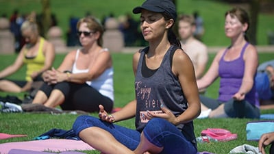 a woman sitting in a yoga pose in a park