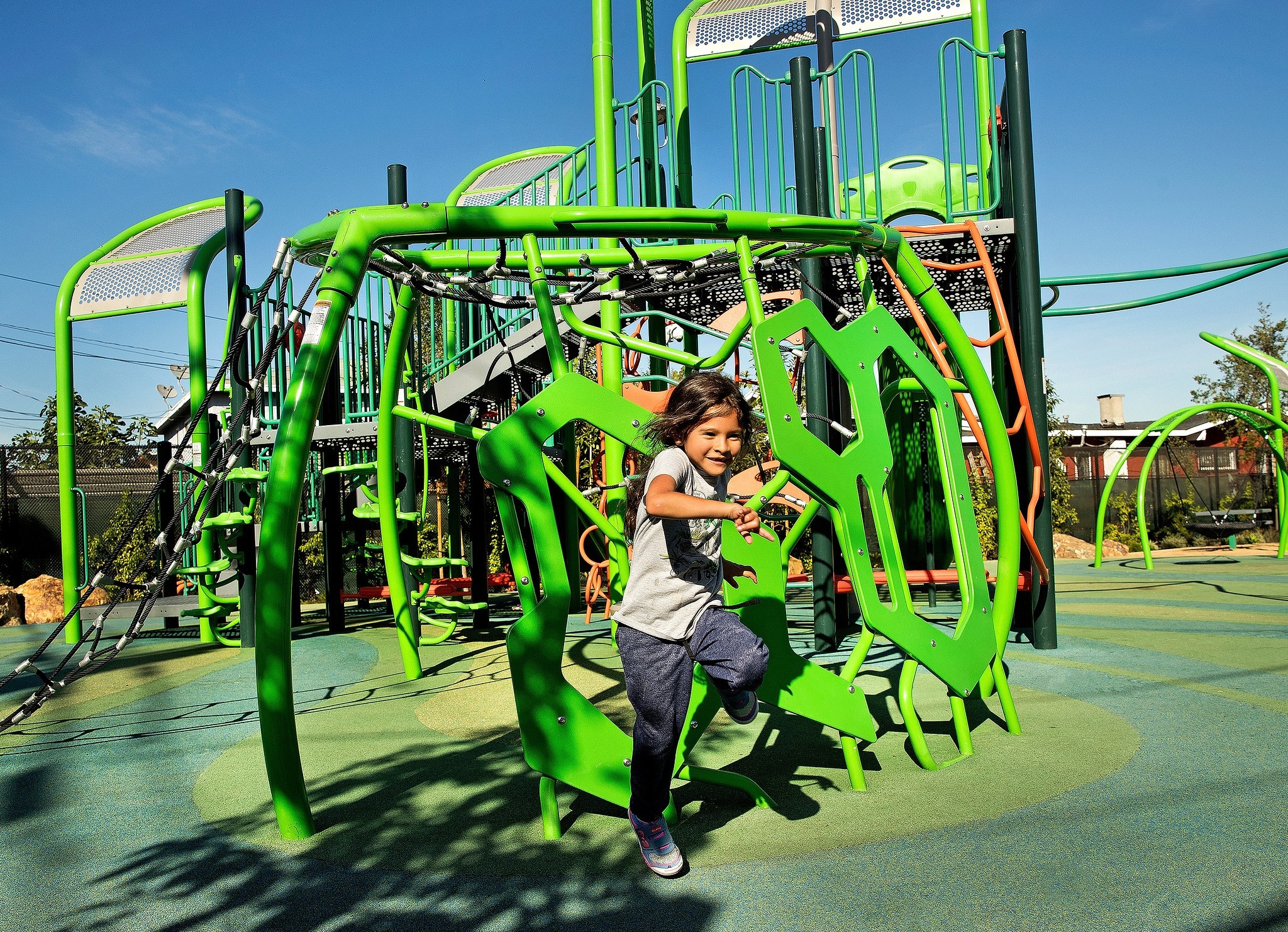 Smiling child playing on a modern, nature-inspired playground structure at South Victoria Park, designed for climbing, exploration, and active play.
