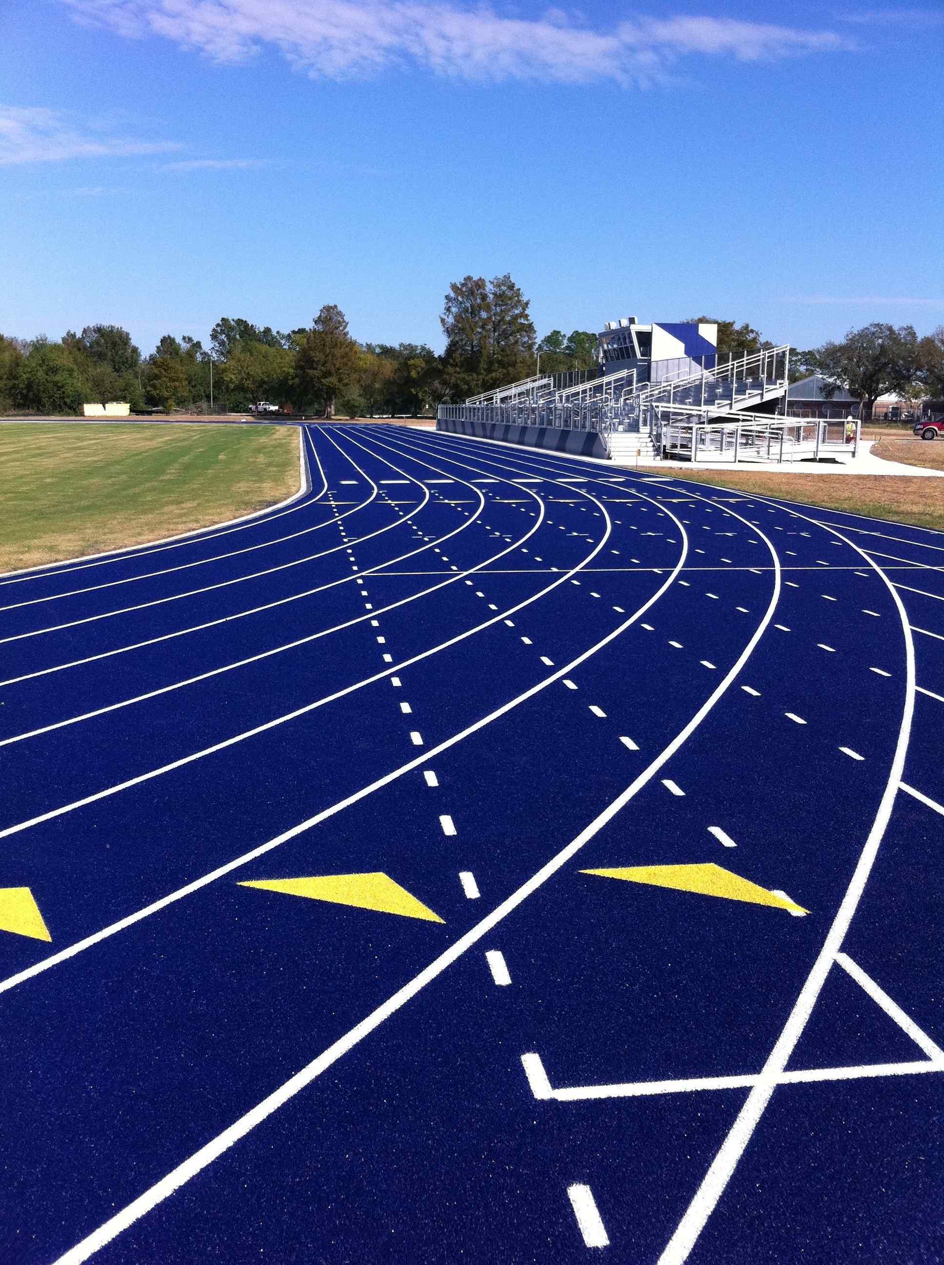 Blue surfacing for running track with yellow arrows along lanes