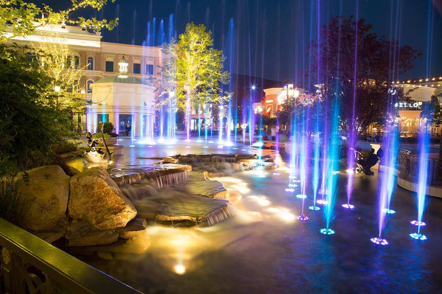 Geyser fountain with blue and purple geysers settled within a creek-style pond