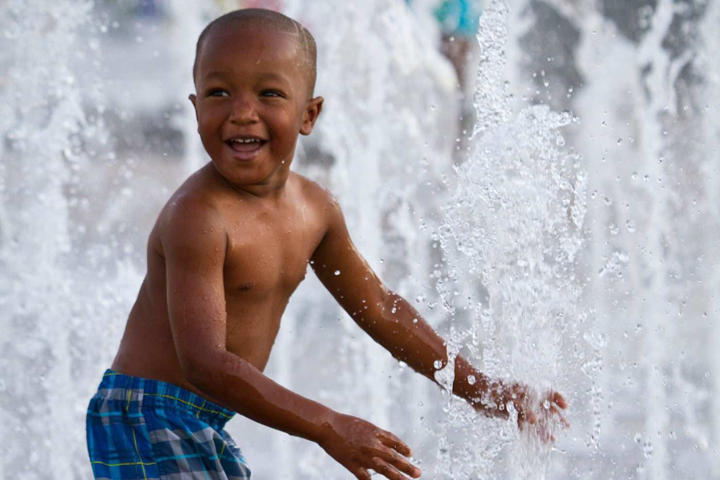 Young Black child playing in a geyser style splash pad