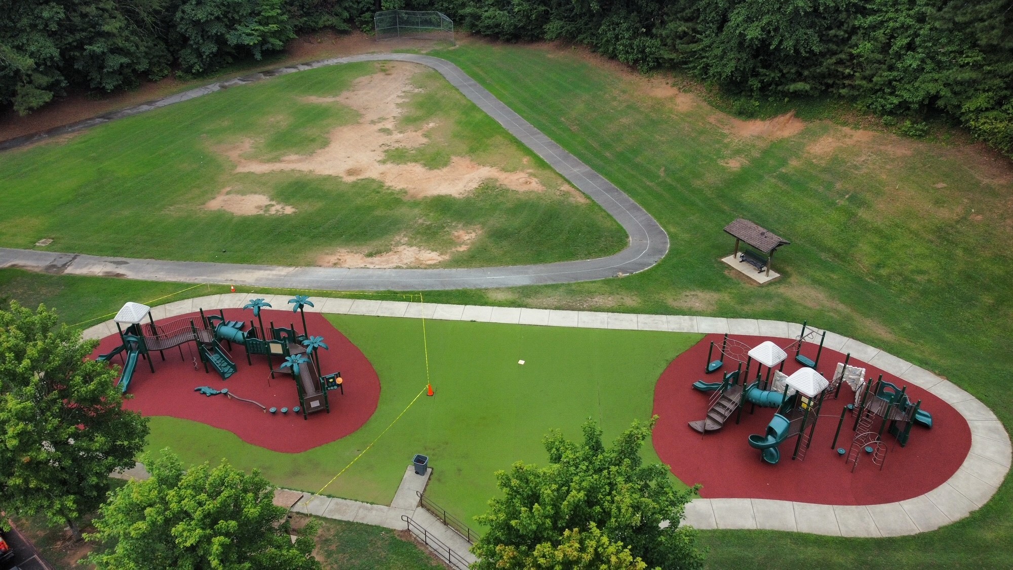 Top view of playground with red surfacing materials under play structure and green surfacing surrounding