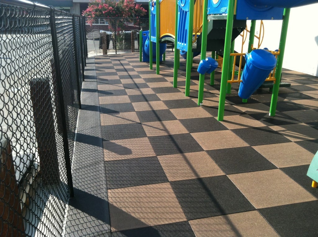 tiled surfacing with a tan and black checker board look under a play structure