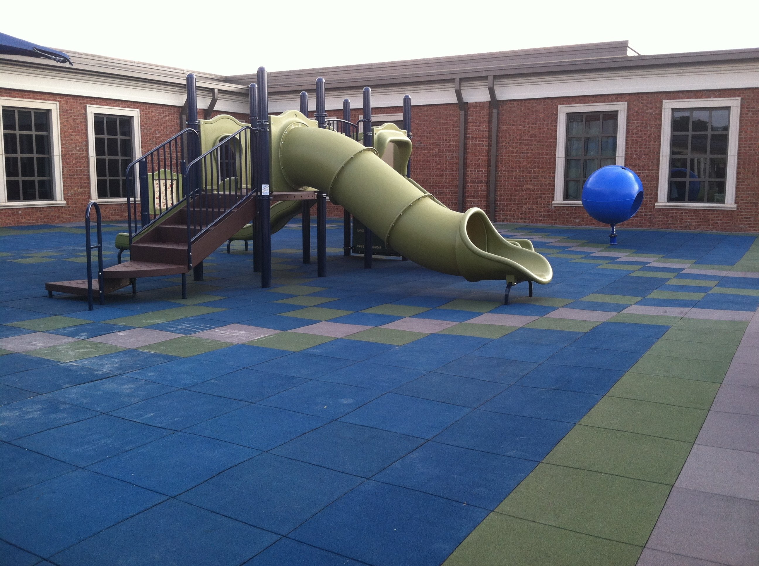 blue and green surfacing tiles under a green slide