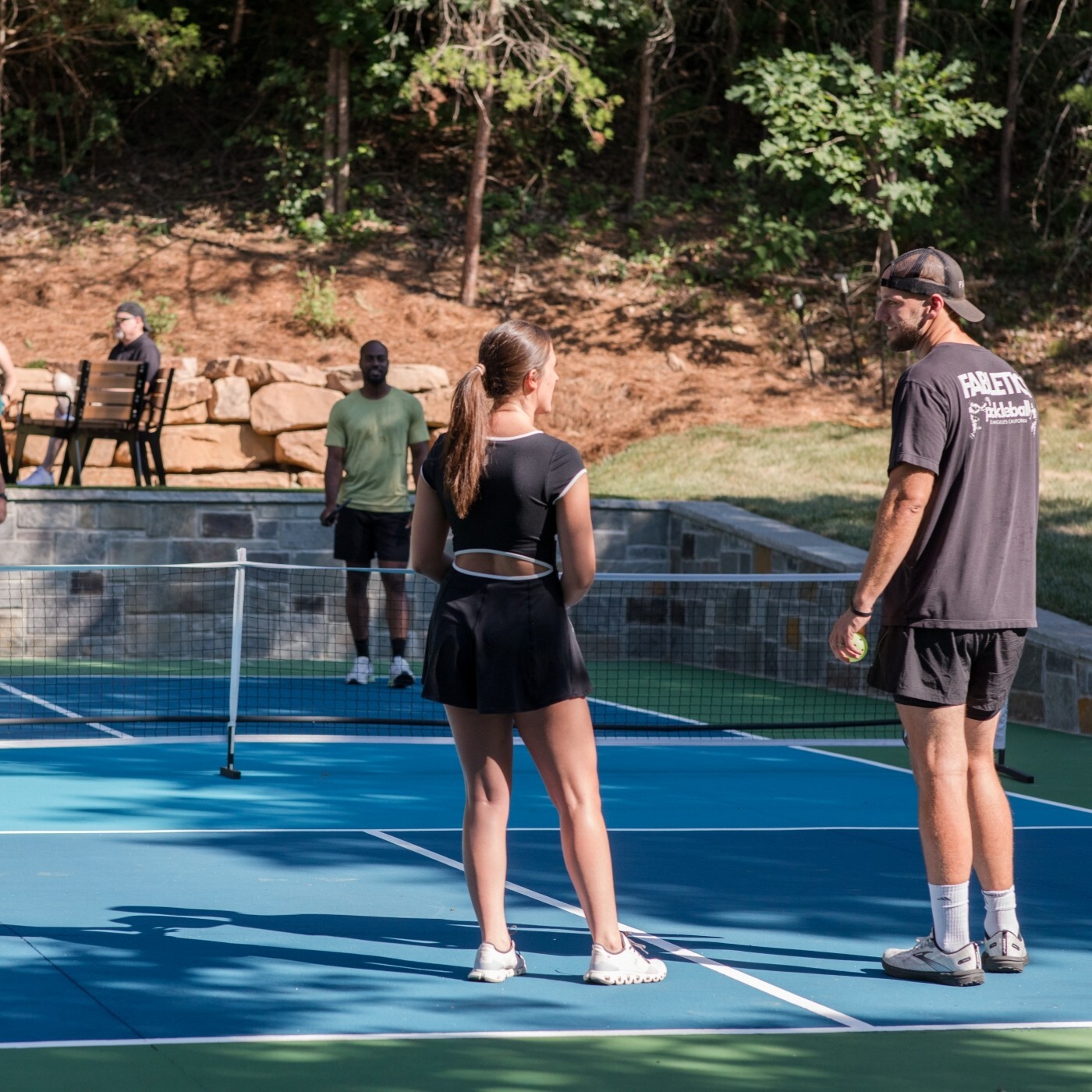 Image of a man and woman talking on a tennis court before the ball is served.
