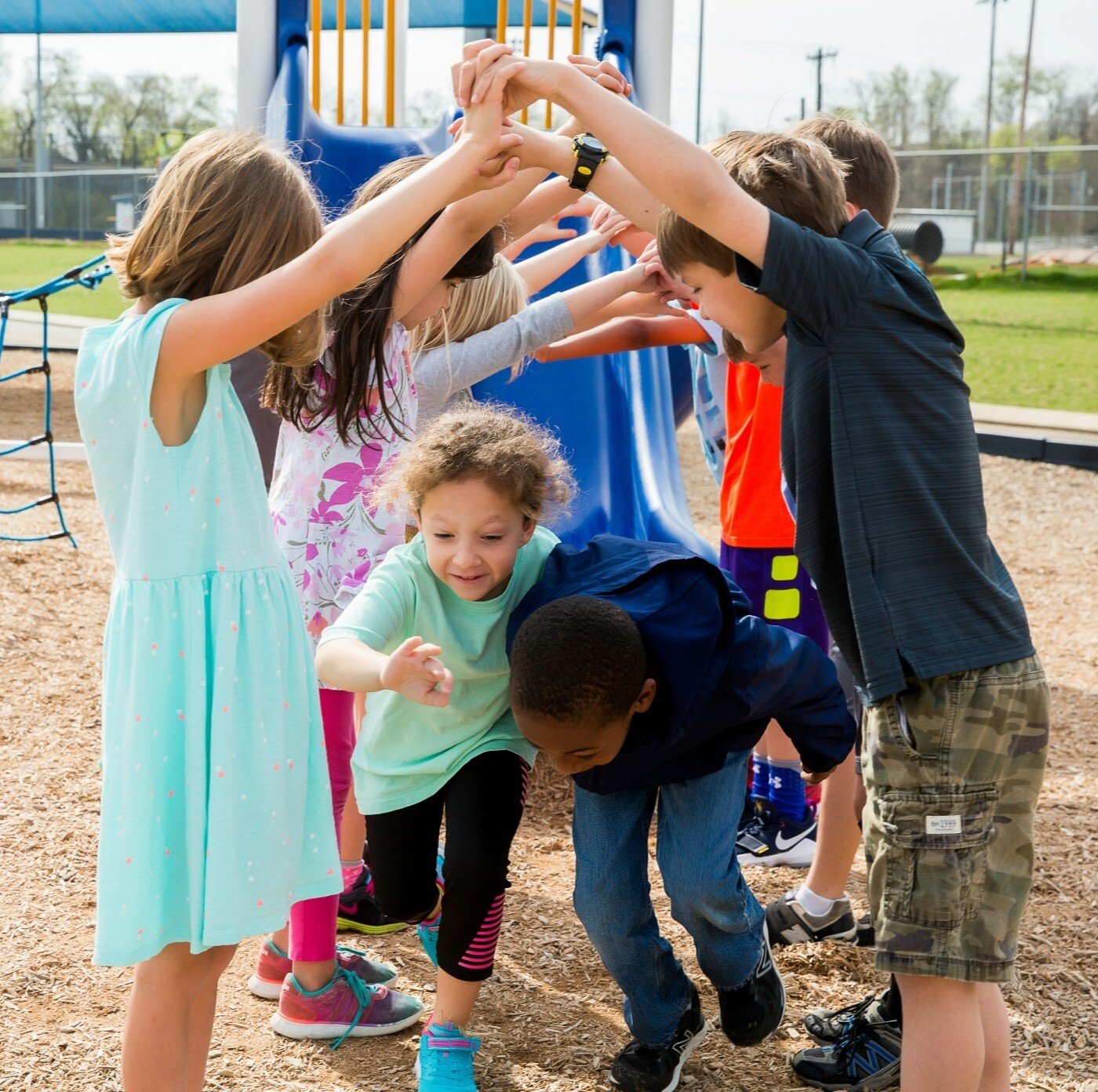Image of two children running underneath the interlocked hands of a group of children