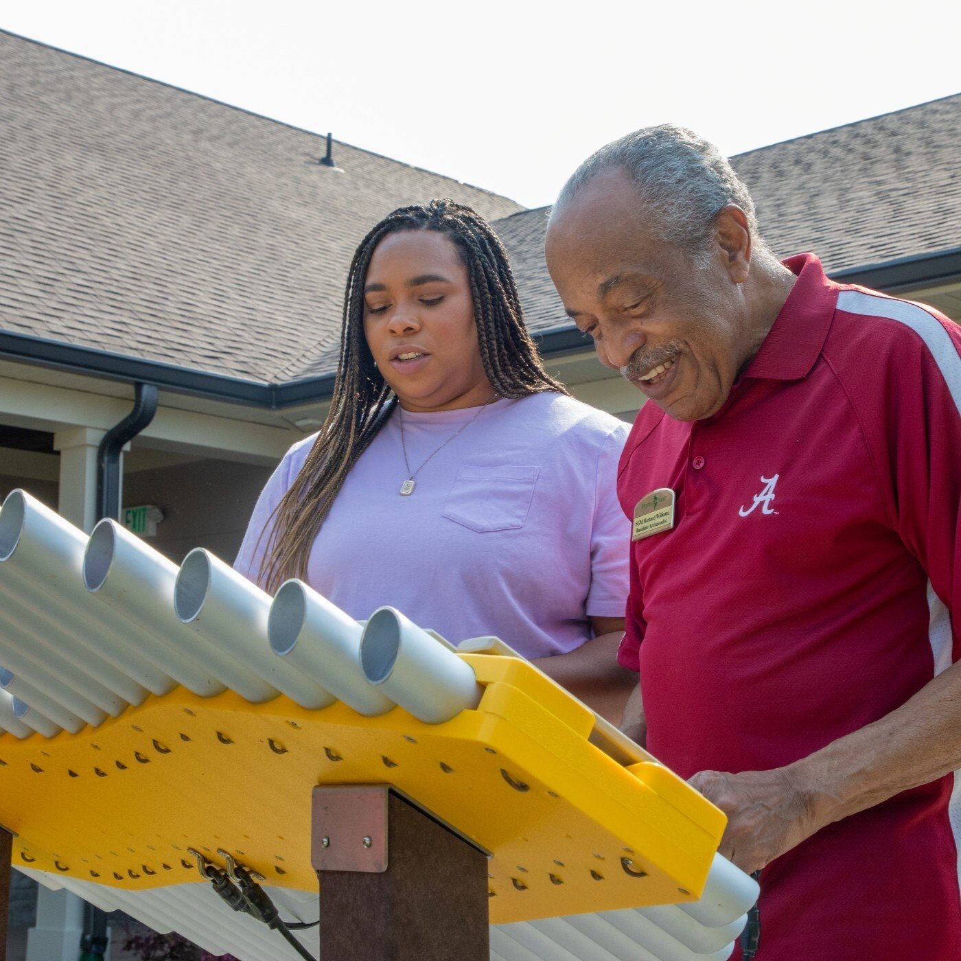 Image of an older Man and girl playing a marimba outside