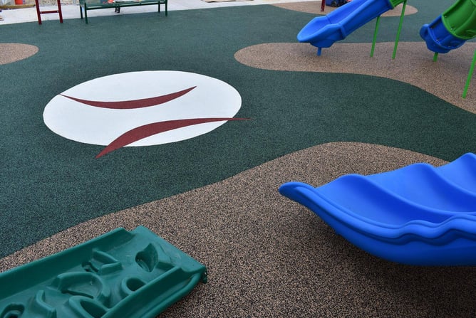 Inclusive Miracle League baseball field with rubberized green and red surfacing, featuring the league’s logo behind home plate.