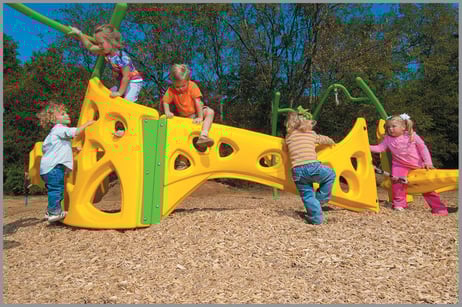 Five children playing on a playground resting on a bed of engineered wood fiber