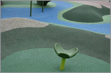 A contoured and shaped playground floor in various shades of green