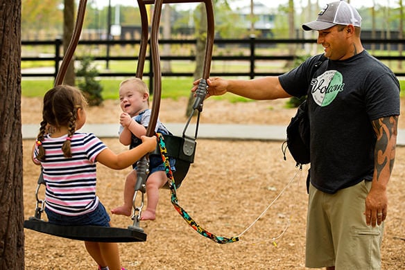 A father swinging two children in an expression swing.