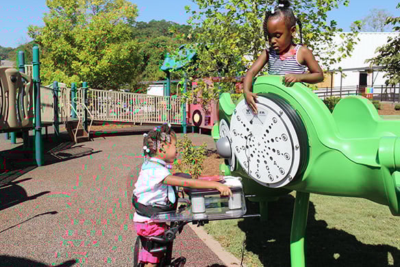 Two black children playing together on lime green playground equipment that resembles an airplane