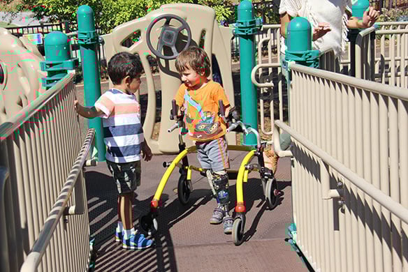 Two children looking at one another on a metal playground bridge