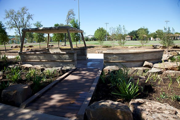 A shaded shelter area with a wood bridge going up to it. This shelter also overlooks at field
