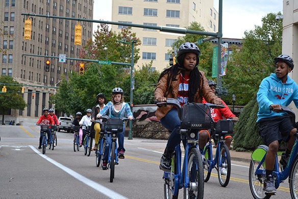 A group of people riding bikes together down a street