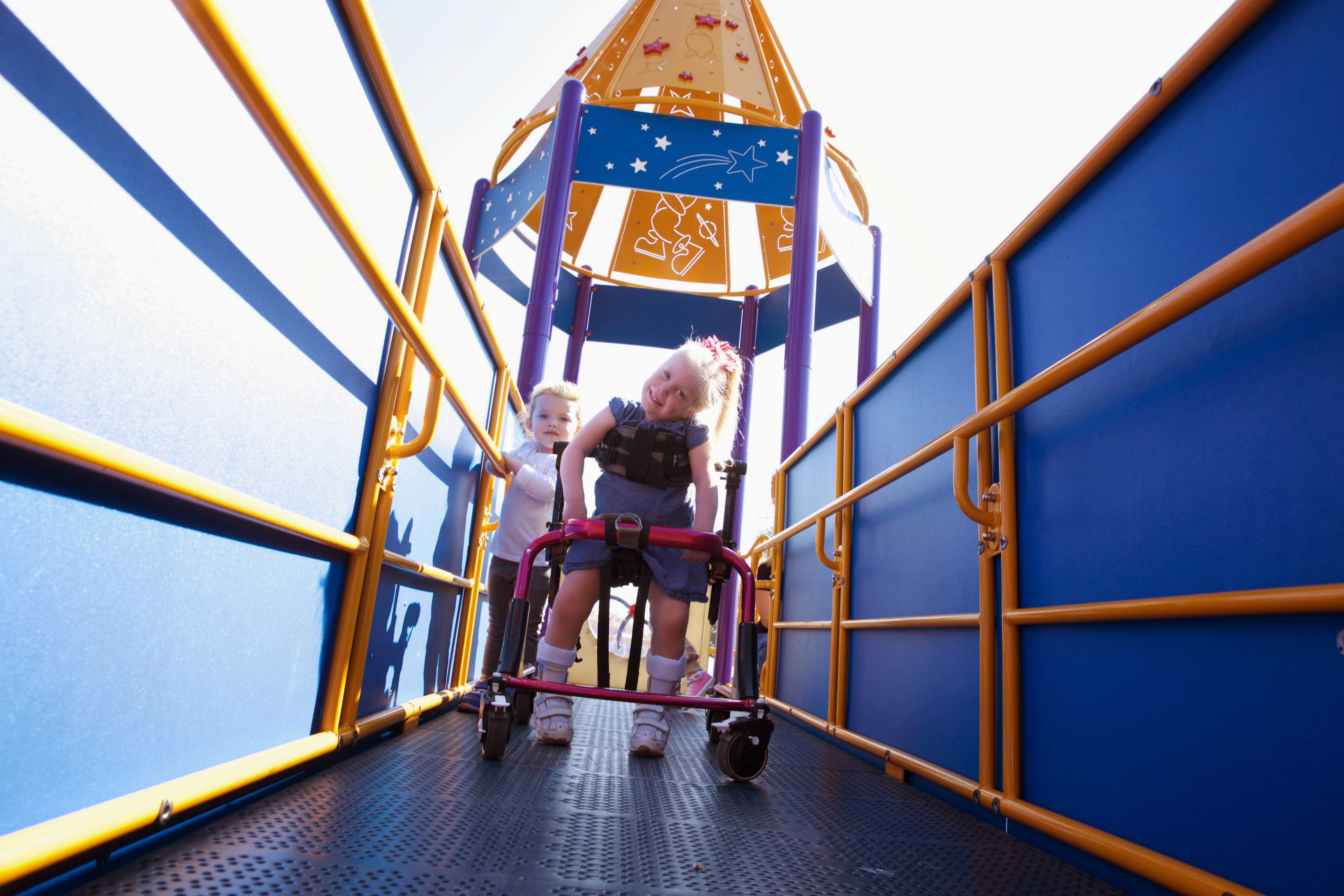 Image of a child in a walker playing in a blue playground set