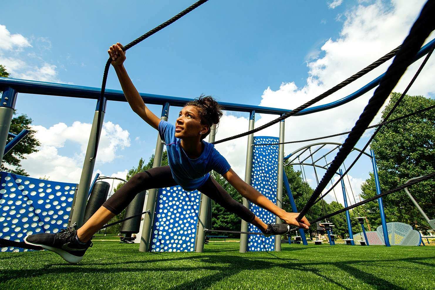Image of a young woman maneuvering across multiple ropes
