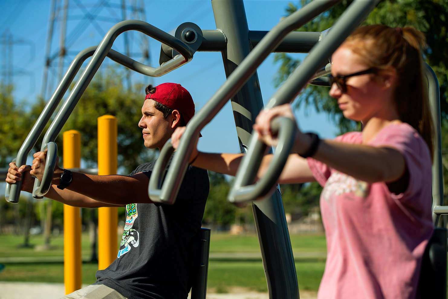 Image of two people exercising on outdoor work equipment