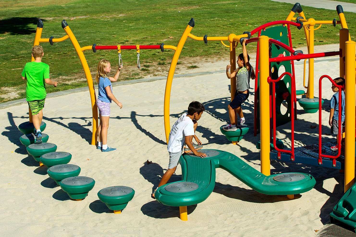 Image of a group of children playing on monkey bars and walking across circular podiums in the ground