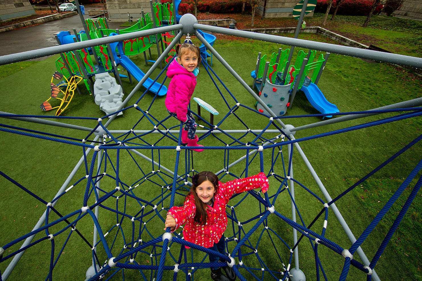 Image of two children climbing through a climbing dome with ropes intertwined through it