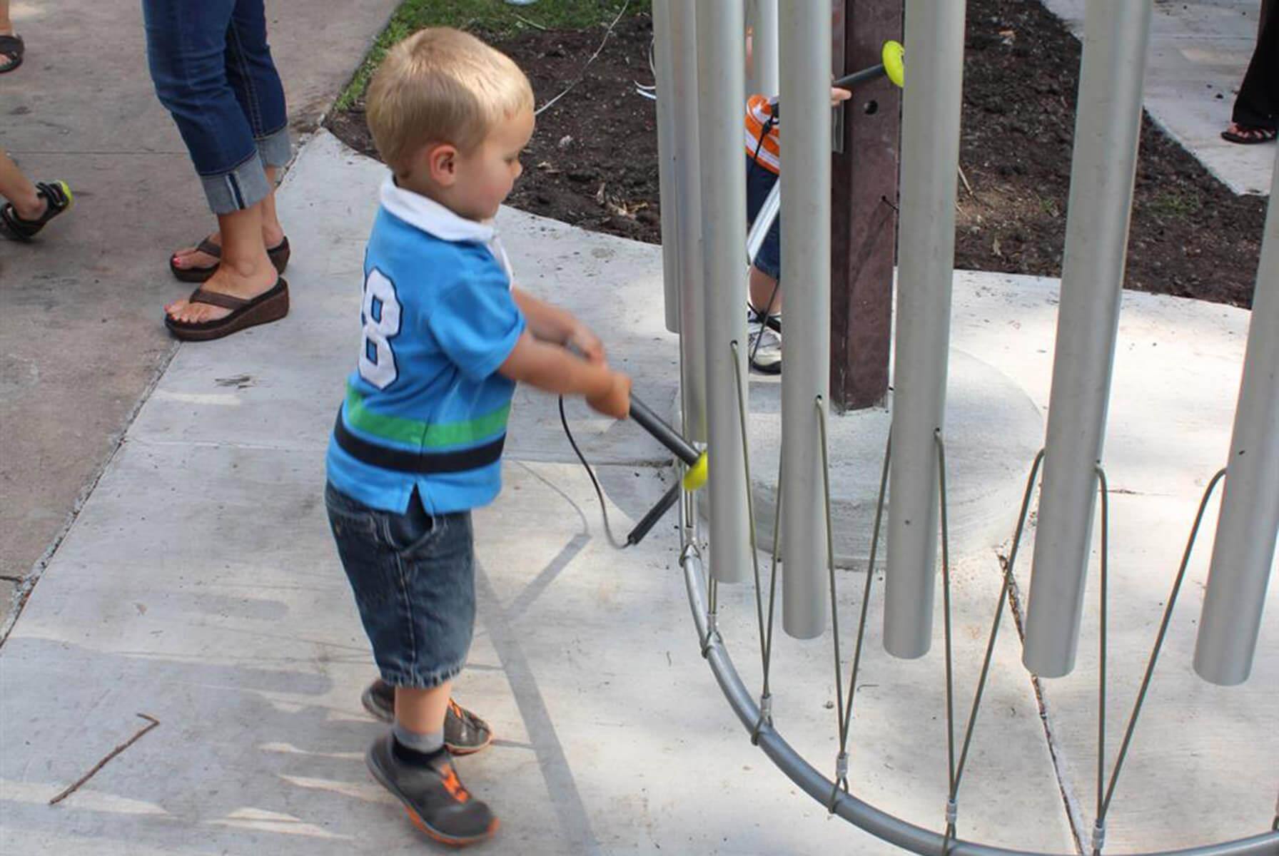 A young child playing with a musical instrument installation