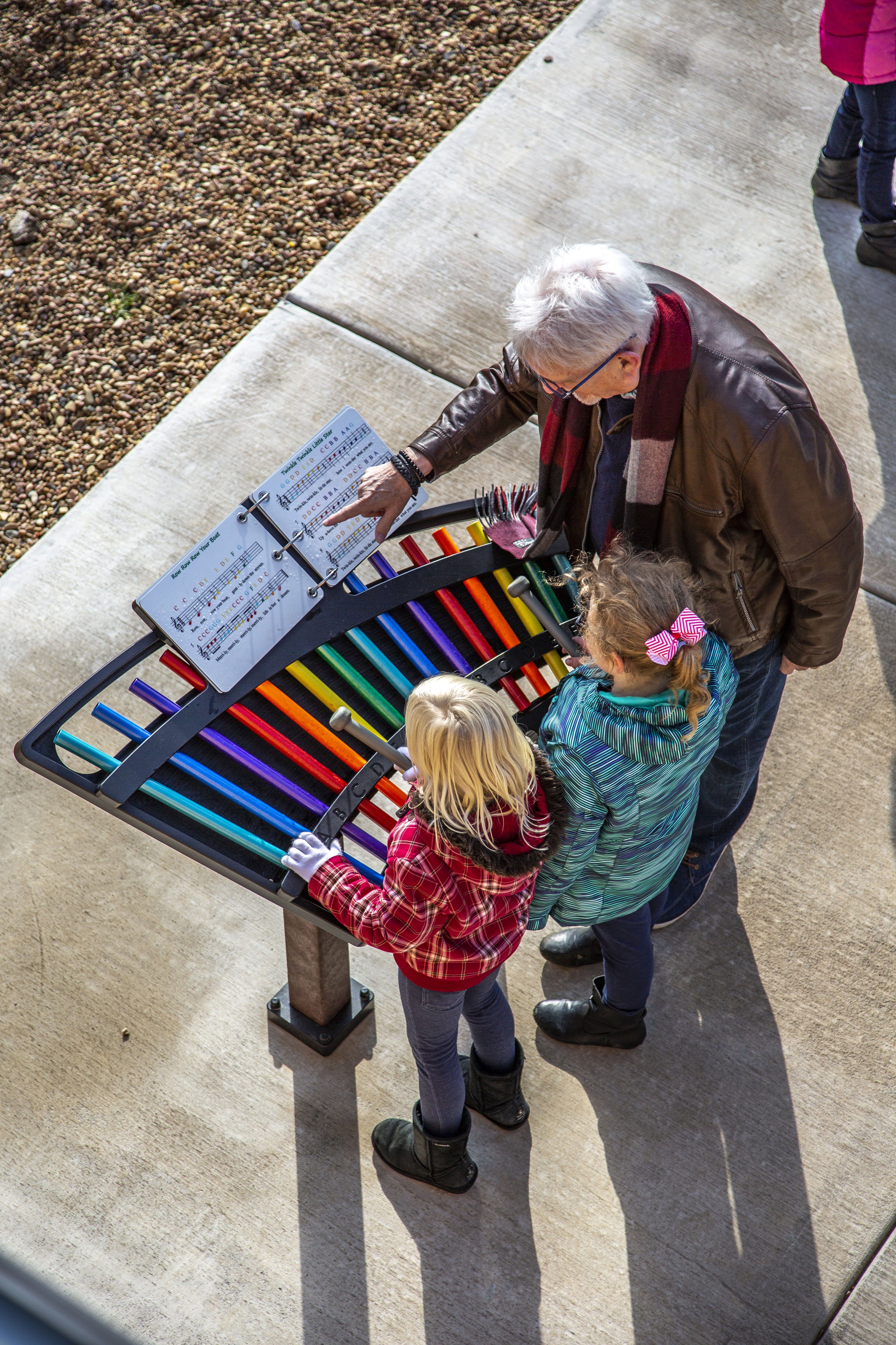 A couple of children being shown how to read music by an elder
