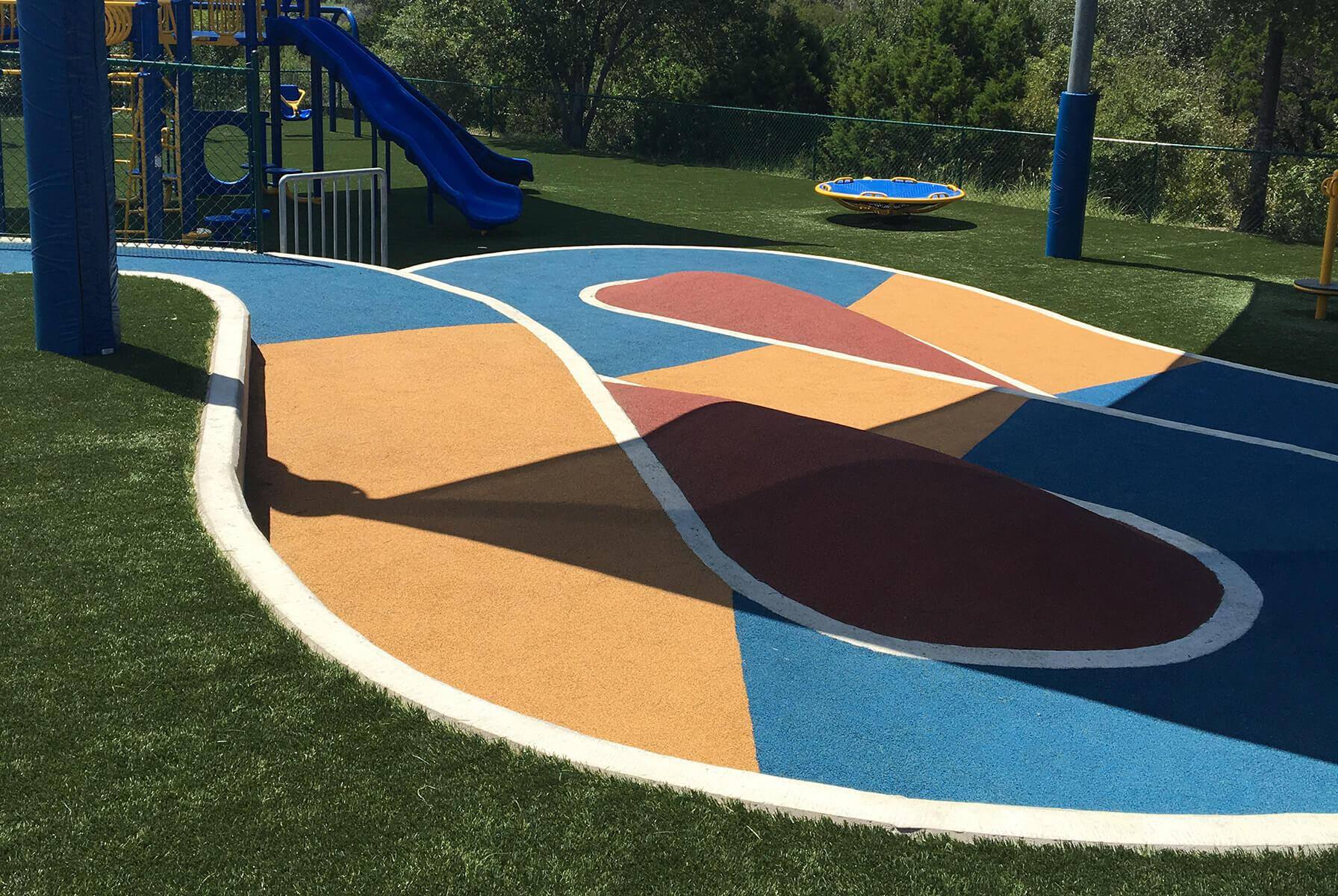 Colorful accessible playground path with ramp and rubber surfacing.