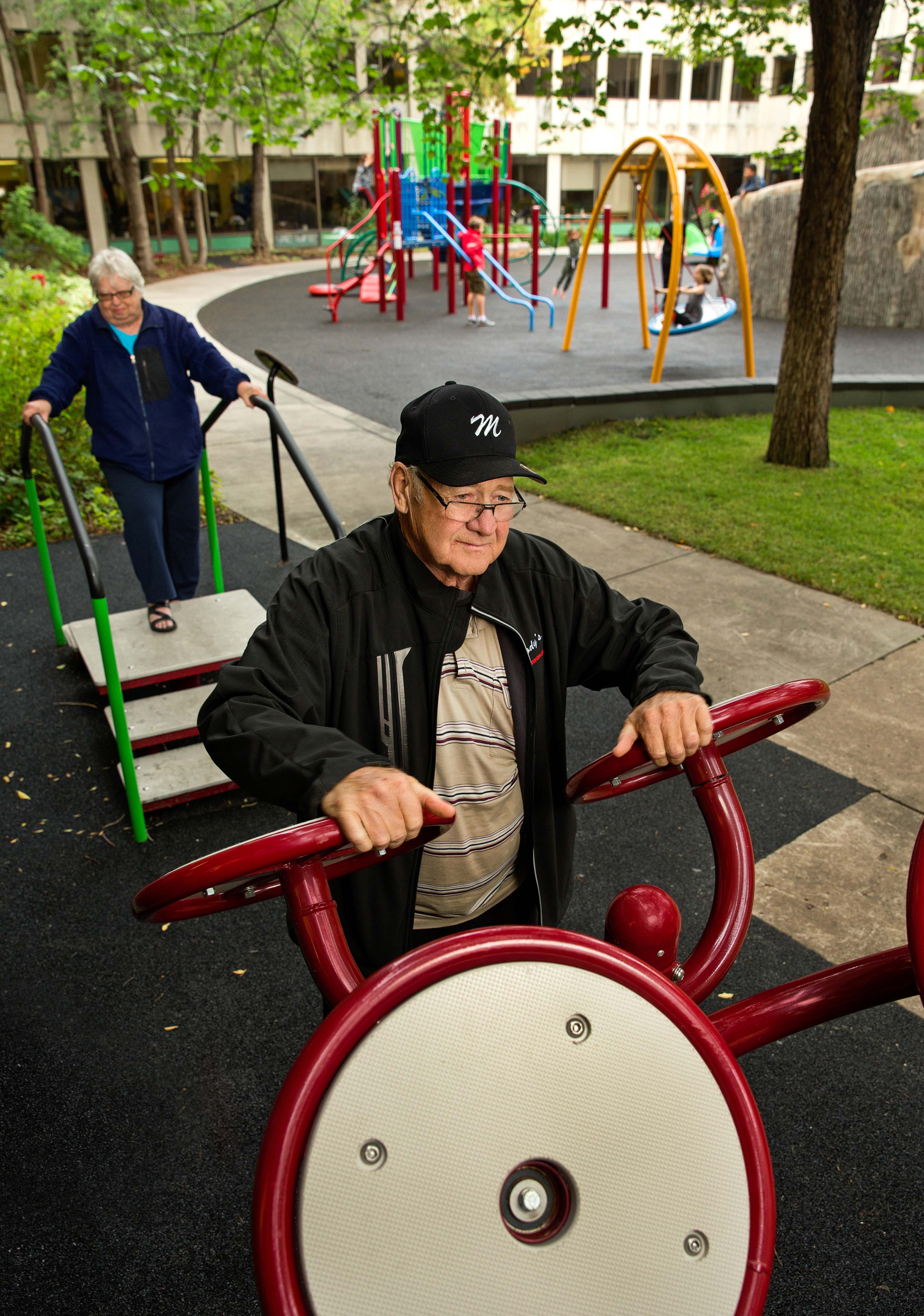 Two elderly individuals using adult outdoor exercise equipment