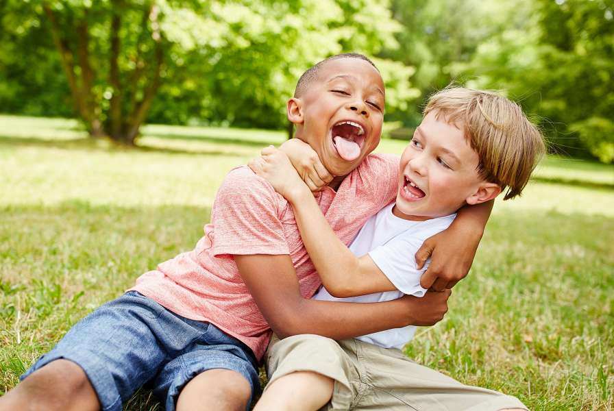 Two boys wresting playfully in the grass