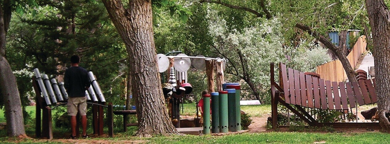 Outdoor musical playground with large percussion instruments in wooded park.