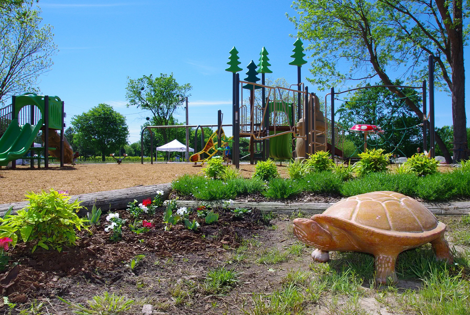 An image of a playground next to playful landscaping, including a tortoise sculpture