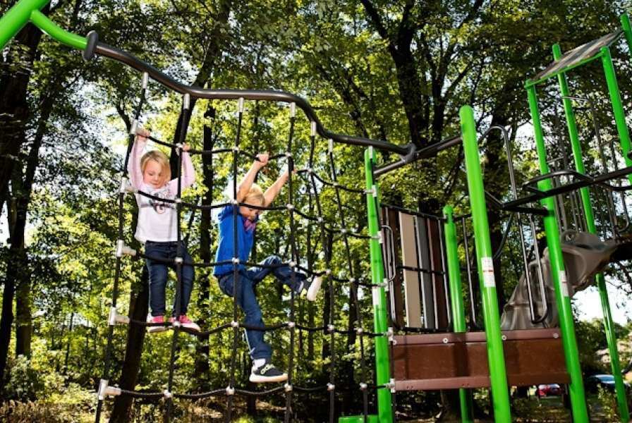 Two children climbing on a vertical playground net