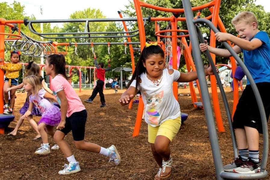 A child running around a piece of playground equipment with other children