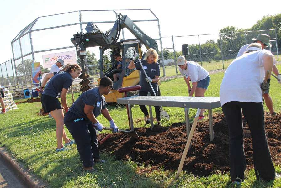 Adults using shovels and heavy machinery to shift earth for a table