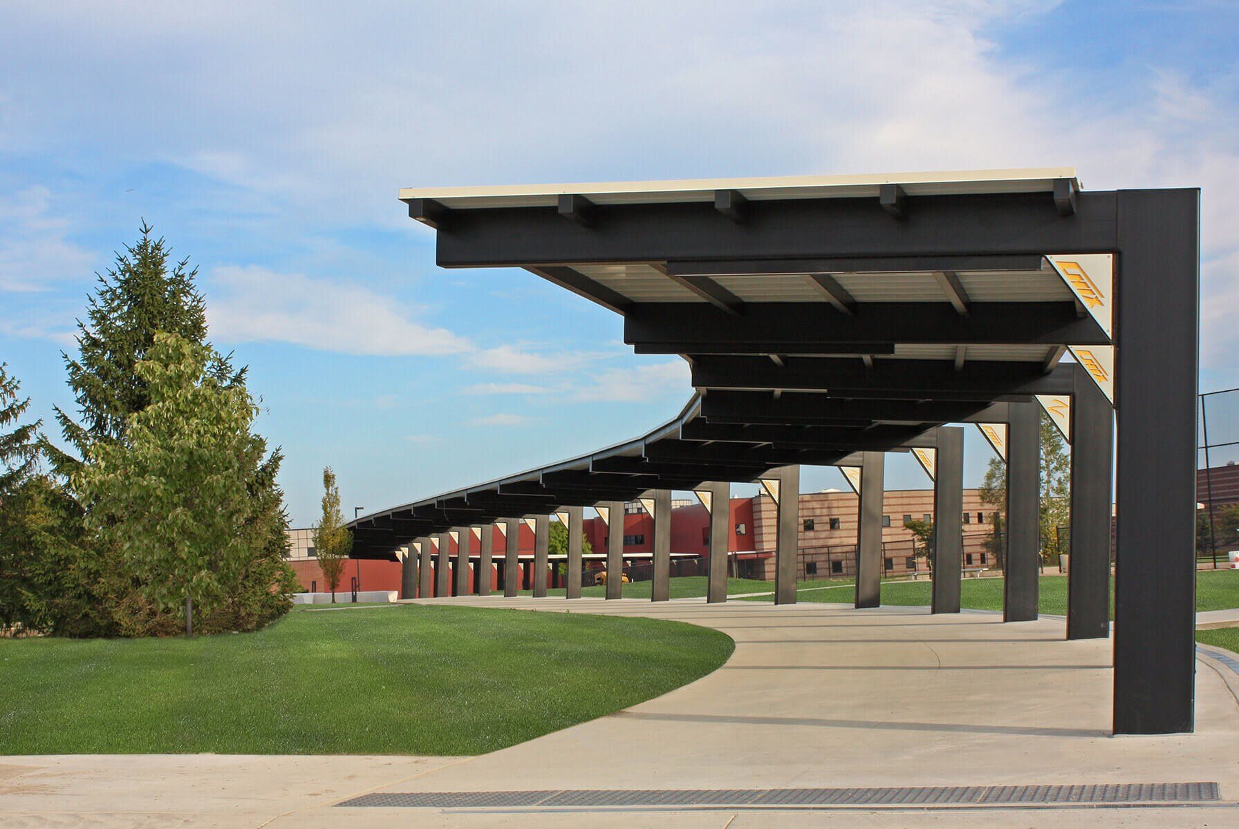 A curving covered walkway over a concrete sidewalk