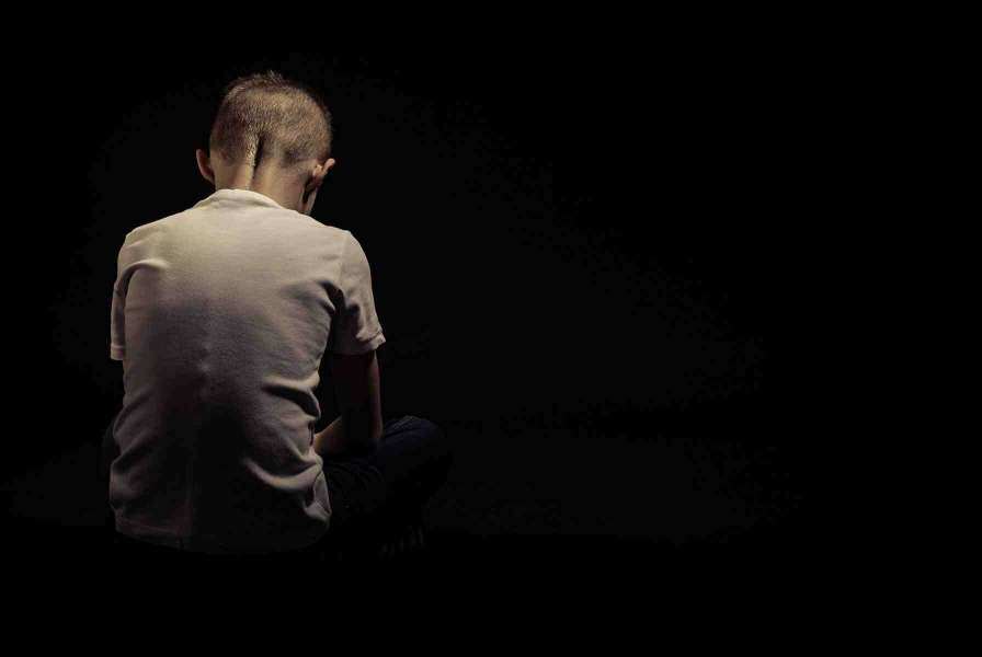 A sad, lonely child sitting with their back to the camera in a featureless void