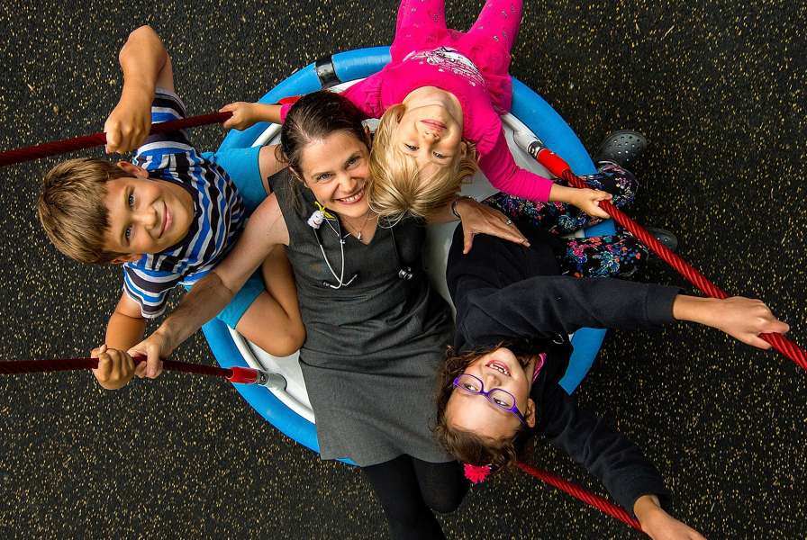A woman and three children piled onto a circular swing, photographed from above