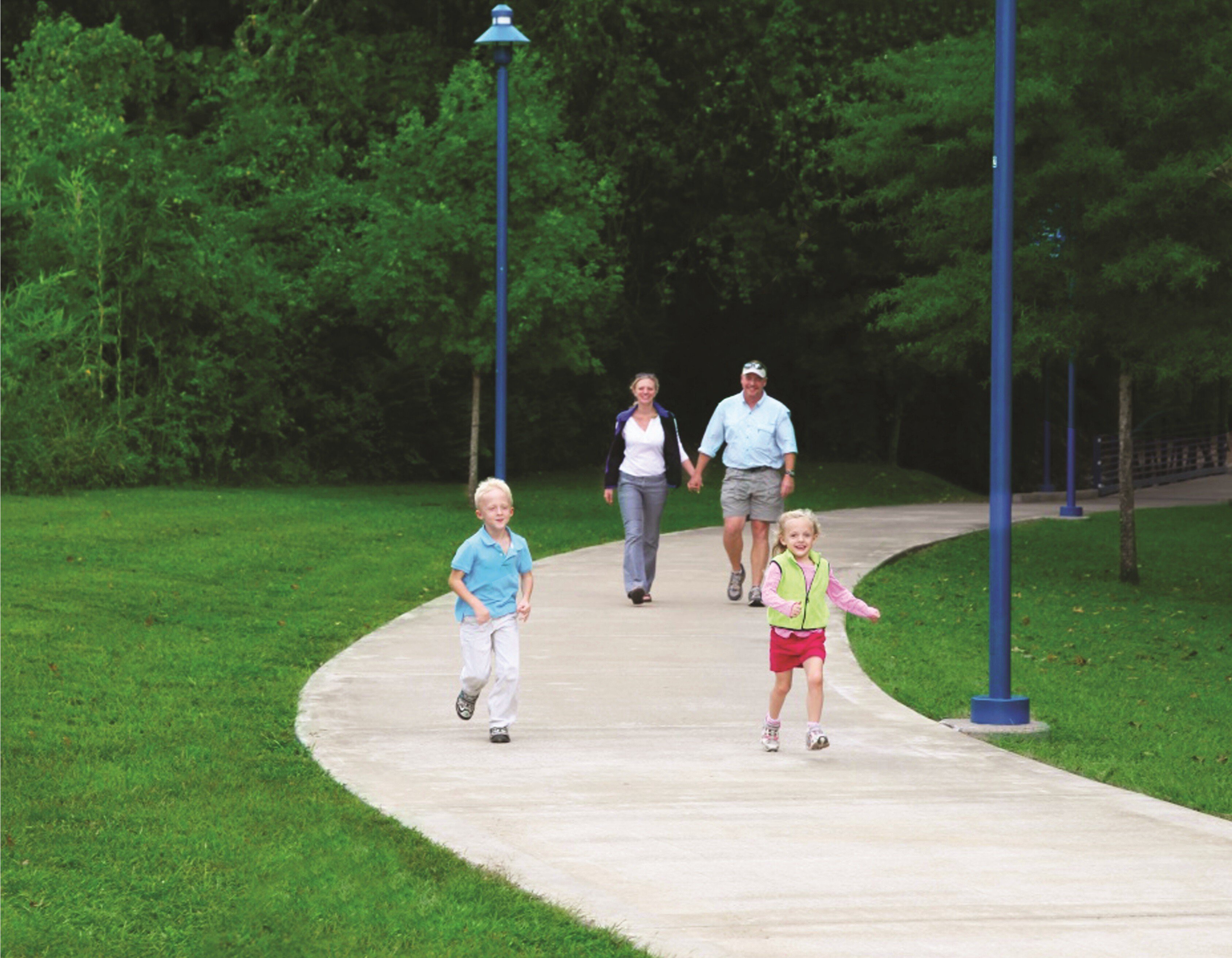 Family walking and kids running on paved park trail.