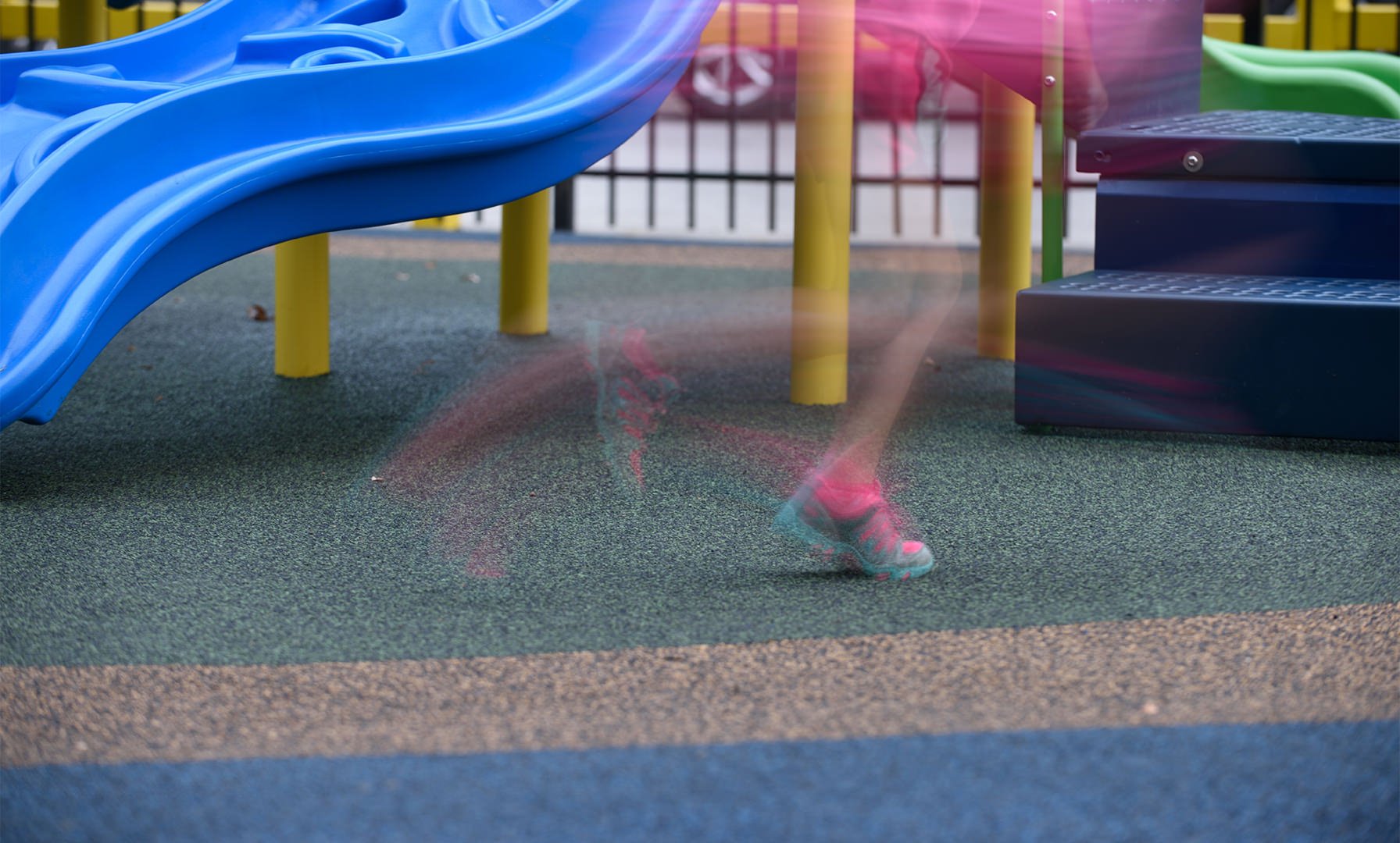 A double-exposed image of a child running on the surface of a playground