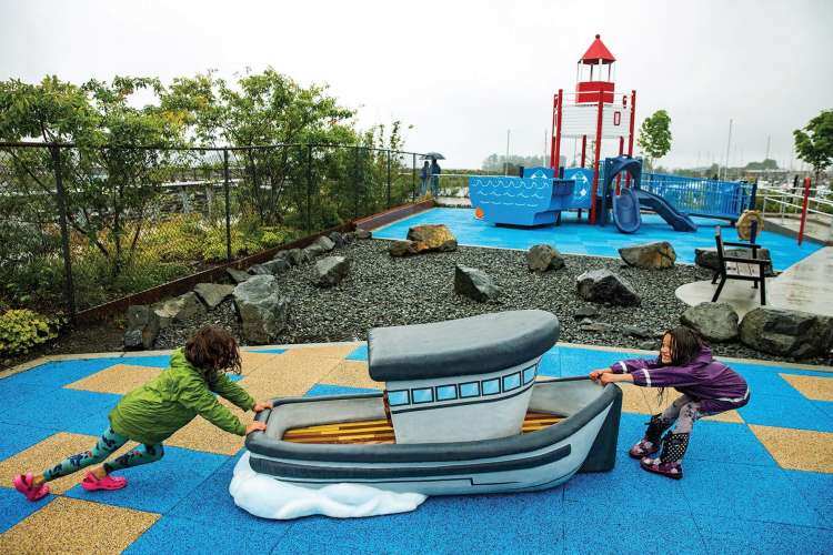 two children playing with a small playground model of a tug boat